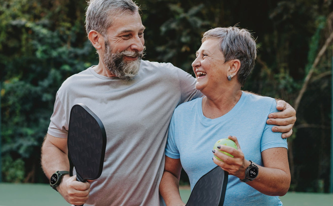 Man and woman holding paddles with 'Stride Smartwatch' branding in the background